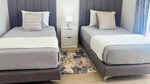 Une chambre double avec deux lits, une table de chevet avec une lampe et un tapis à motifs.