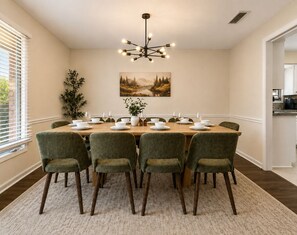 A dining room with a table set for six, six chairs, a chandelier, and a painting on the wall. - Sleeps 14 ~ MiniGolf, HotTub, MovieRm, Sauna, Firepit (Columbus)