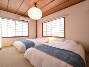 A room with two beds, a ceiling fan, and a window with a view. - Imakusa-so, Nara, Naramachi - The Steam Bath House - (奈良市福智院町)