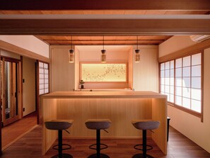 A modern interior with a wooden bar area, three stools, pendant lighting, and a view through a shoji screen. - Imakusa-so, Nara, Naramachi - The Steam Bath House - (奈良市福智院町)