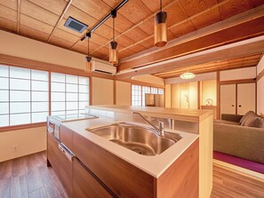 A modern kitchen with a wooden island, stainless steel sink, and pendant lighting. - Imakusa-so, Nara, Naramachi - The Steam Bath House - (奈良市福智院町)