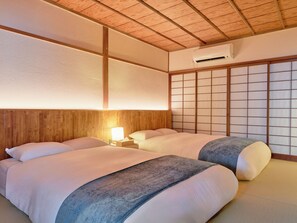A hotel room with two beds, a wooden ceiling, a sliding shoji screen, and an air conditioning unit. - Imakusa-so, Nara, Naramachi - The Steam Bath House - (奈良市福智院町)