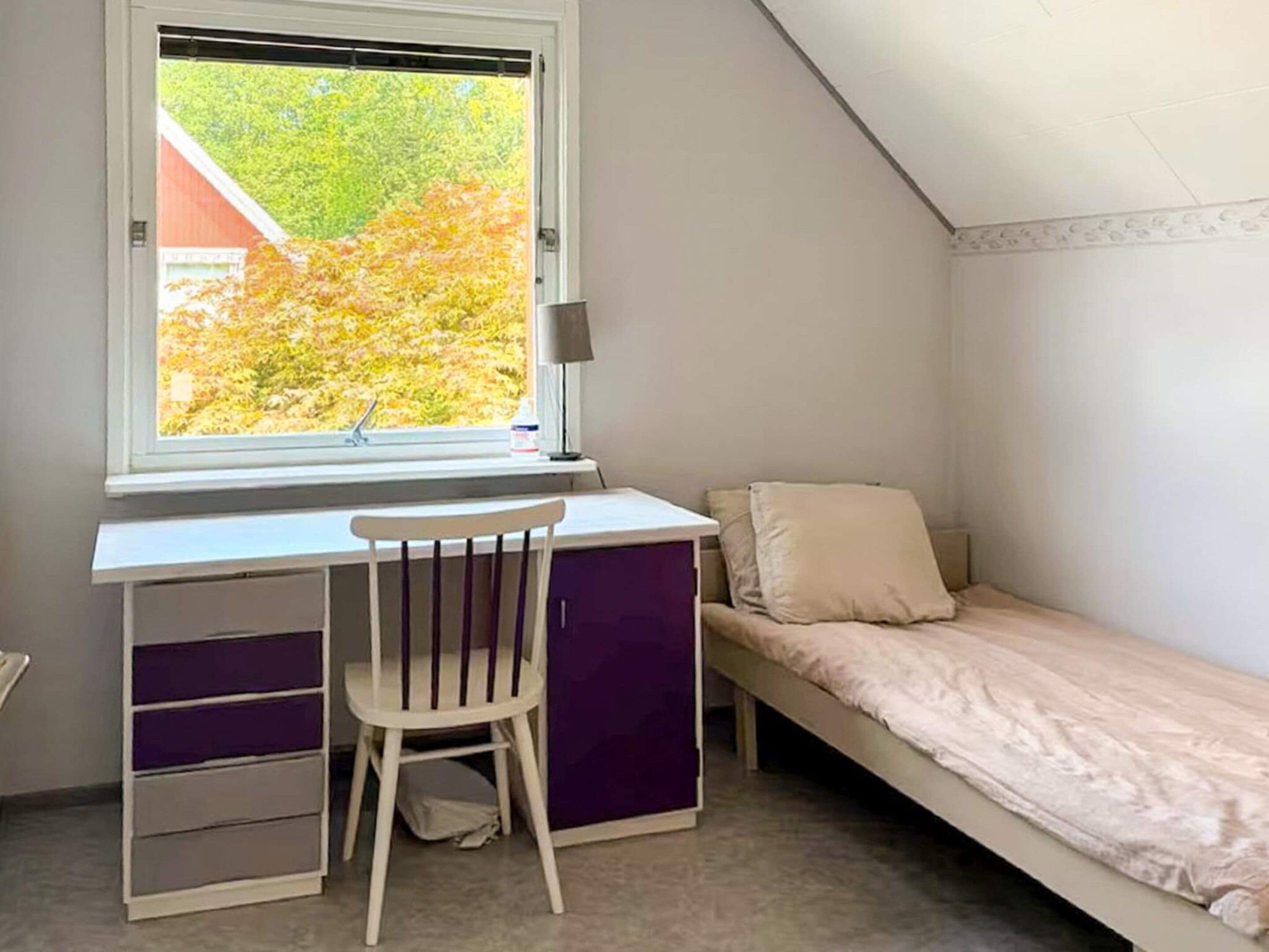 A dormitory room with a desk, chair, and bunk bed.