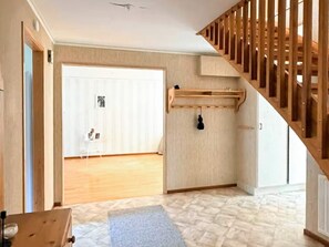 A room with a wooden staircase, a white door, and a small table with a mat. - 5 Person Holiday Home in Brakne-hoby (Brakne-Hoby)
