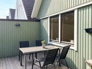 A patio with a table and chairs, a potted plant, and a window with blinds. - 5 Person Holiday Home in Brakne-hoby (Brakne-Hoby)