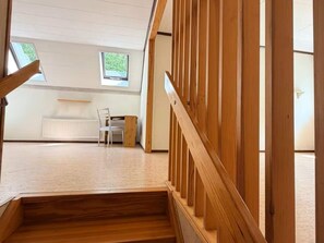 A wooden staircase leading to a room with a white radiator, a chair, and a window. - 5 Person Holiday Home in Brakne-hoby (Brakne-Hoby)