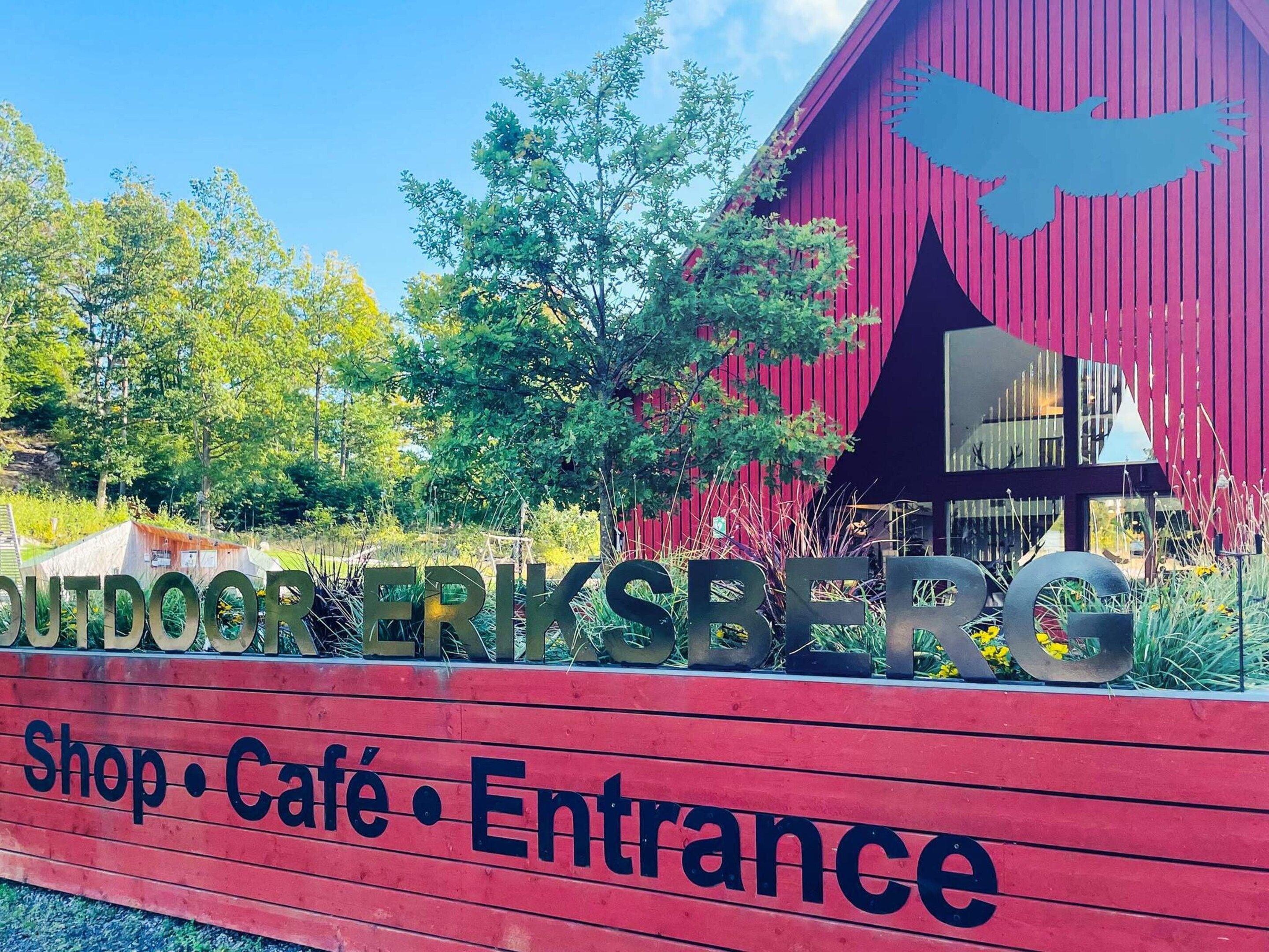 Un bâtiment rouge avec une enseigne indiquant : « Boutique ERIKSBERG en plein air • Café • Entrée ».