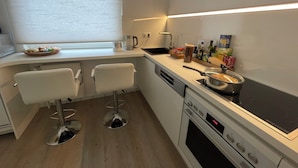 Una cocina moderna con horno empotrado, estufa y una ventana con persianas.