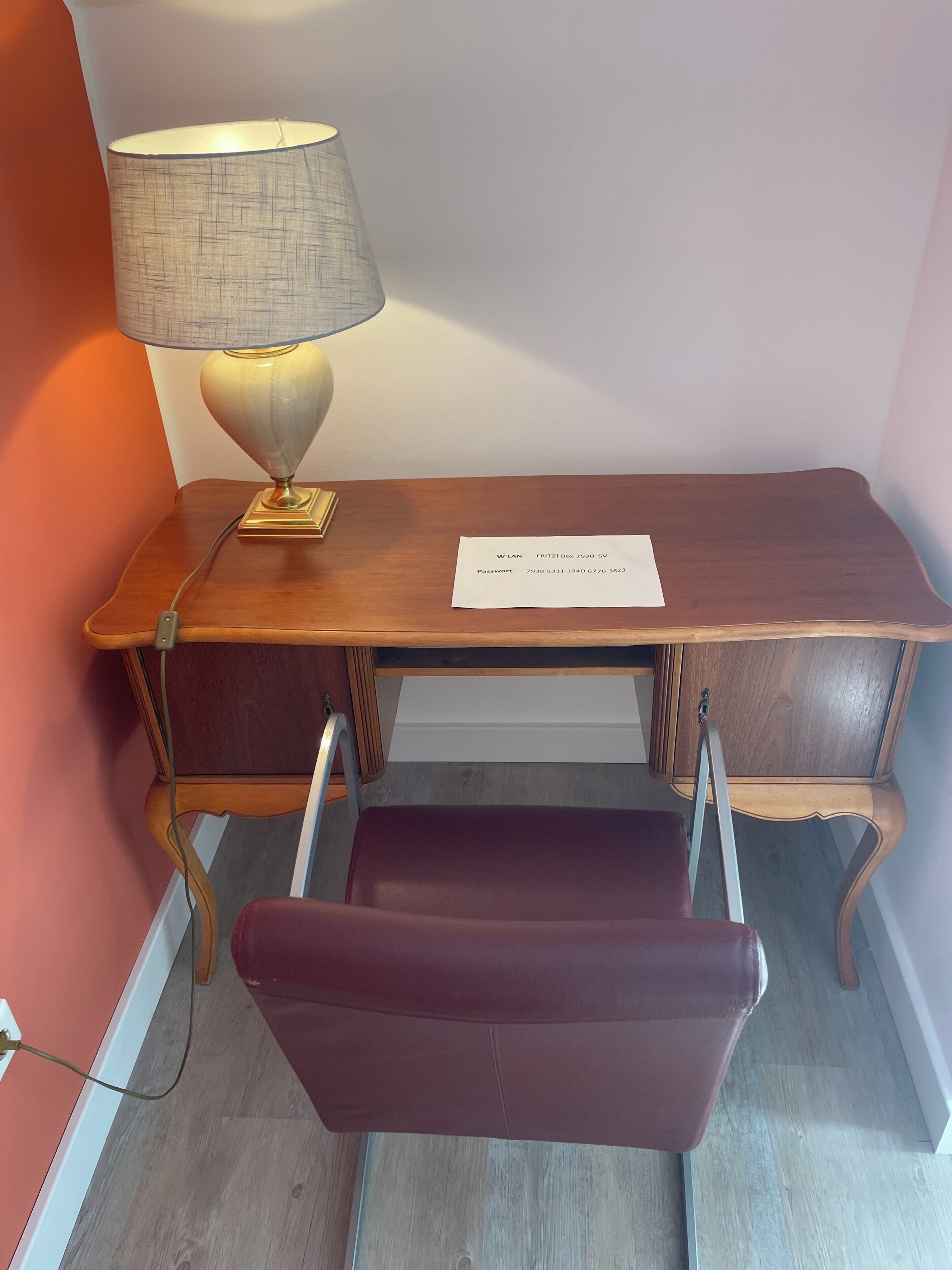 Ein Holztisch mit einer Lampe, einem Stuhl und einem Blatt Papier mit Text.