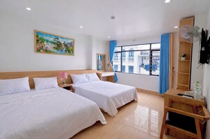 Habitación de hotel con dos camas, un cuadro, una ventana con cortinas, un televisor y una mesita de noche de madera.