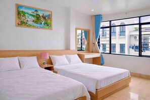 Habitación de hotel con dos camas, una mesita de noche, una lámpara, una ventana con cortinas y un cuadro en la pared.