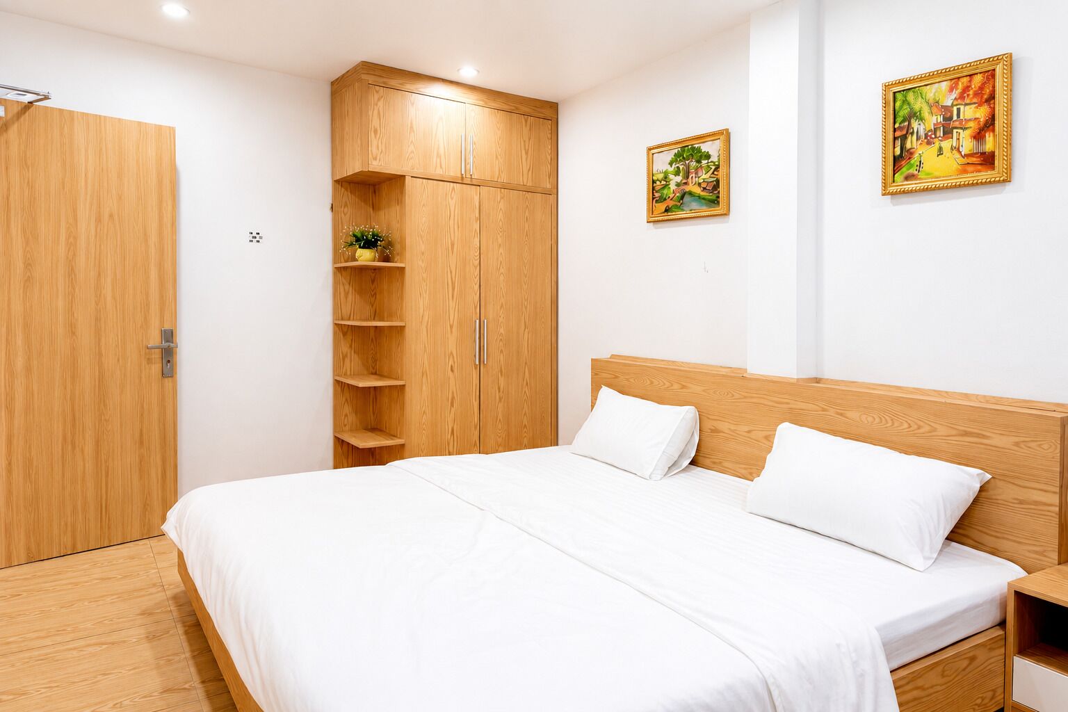 A bedroom with a wooden bed, a wardrobe, and two paintings on the wall.