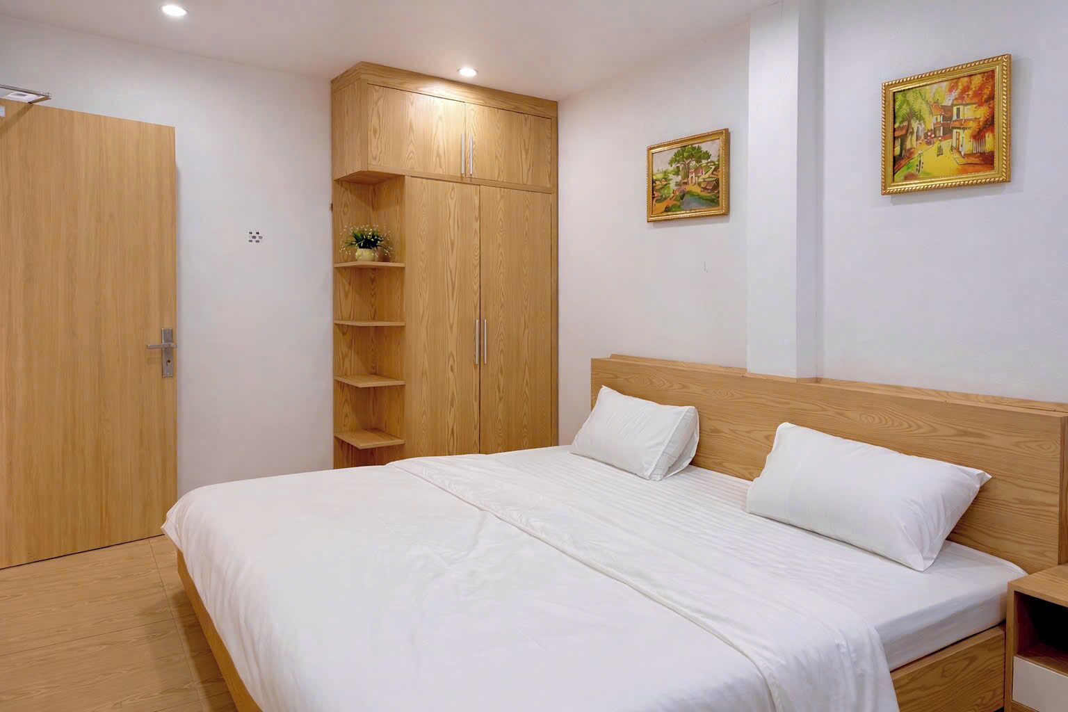 Un dormitorio con una cama de madera, un armario y dos cuadros en la pared.