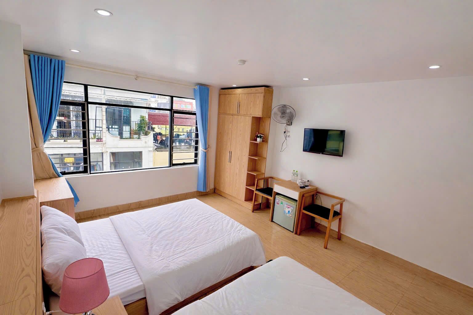 Een hotelkamer met twee bedden, een bureau met een computer, een televisie en een kledingkast.