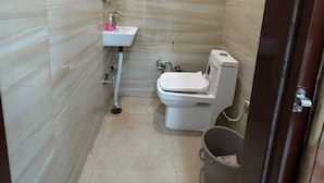 A compact bathroom with a toilet, sink, and a trash bin. - Om Home Stay (Agra)