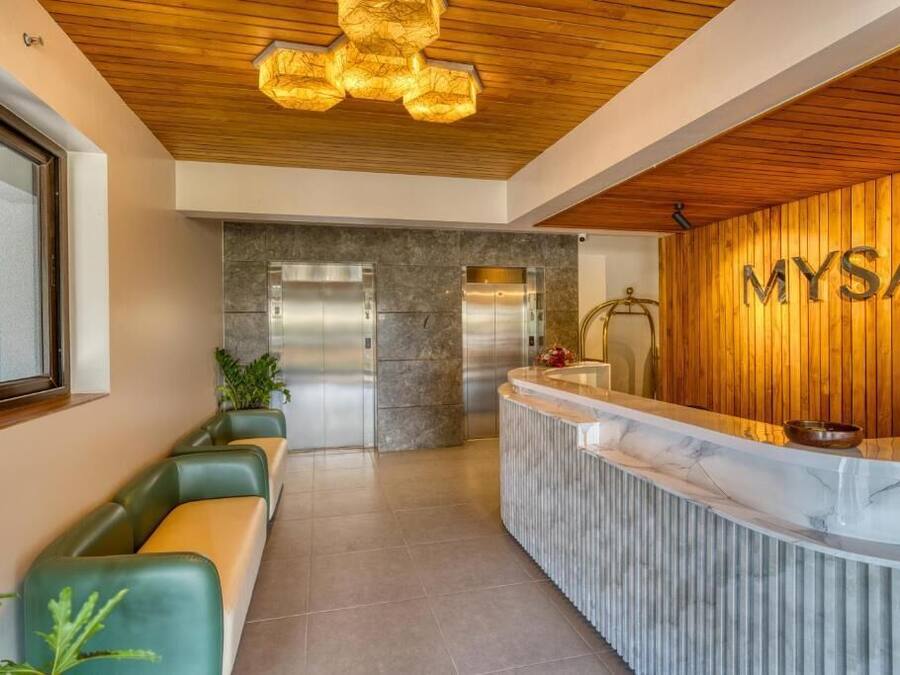 A reception area with a wooden reception desk, a marble counter, and a seating area with green and orange chairs.
