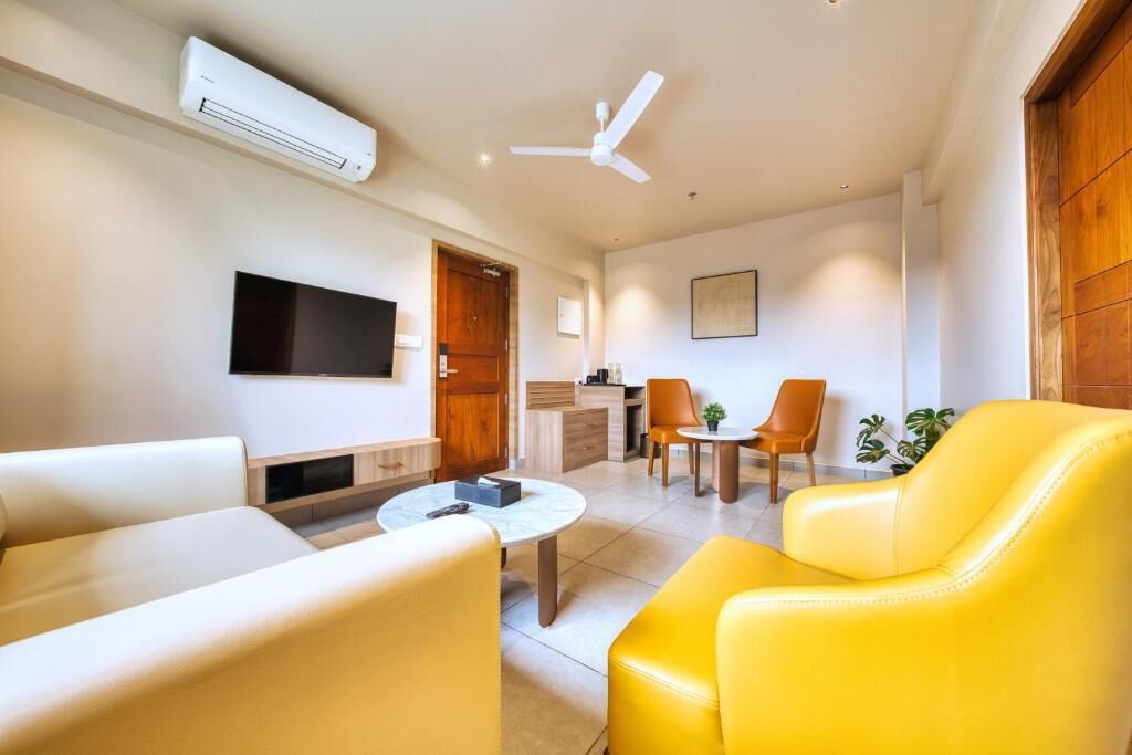 Una sala de estar moderna con un televisor de pantalla plana, un ventilador de techo y un sofá de cuero amarillo.