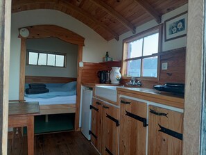 A compact room with a bed, a small kitchenette, and a window. - Country farm Roulotte, stunning sunrises & sunsets, private patio (Dettey)