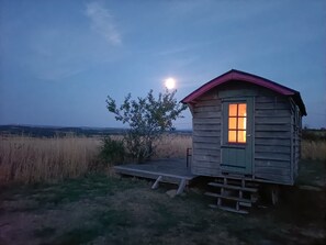 A small wooden cabin with a porch, a single window with a view of the landscape, and a tree beside it. - Country farm Roulotte, stunning sunrises & sunsets, private patio (Dettey)