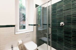 Un baño moderno con inodoro, cabina de ducha de vidrio y ventana.