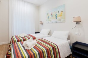Ein Hotelzimmer mit zwei Betten, einem Bild an der Wand und einem Nachttisch mit Lampe.
