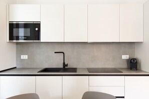 A modern kitchen with a Bosch microwave, a black faucet, and a coffee machine. - Casa e Appartamento Vacanze Gallese 4 (Roma)