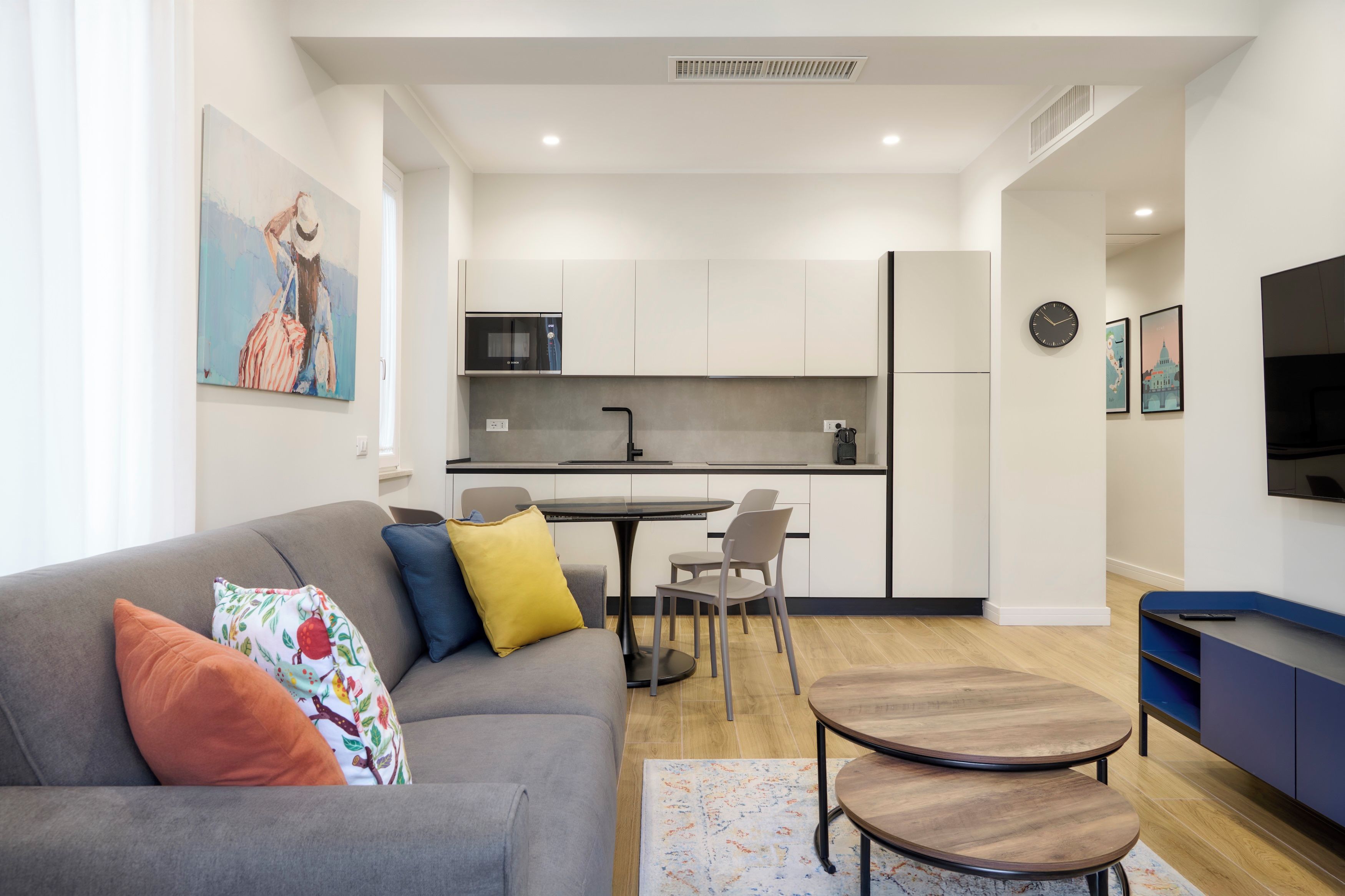 A modern living room with a grey sofa, a coffee table, and a TV stand.