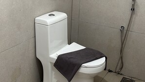 Un baño moderno con inodoro blanco, toallero y ducha.