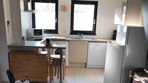 Una cocina moderna con una isla central, un comedor con una mesa redonda y una pequeña planta decorativa.