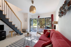 A modern living room with a staircase, a red sofa, a small round table, and a television.
