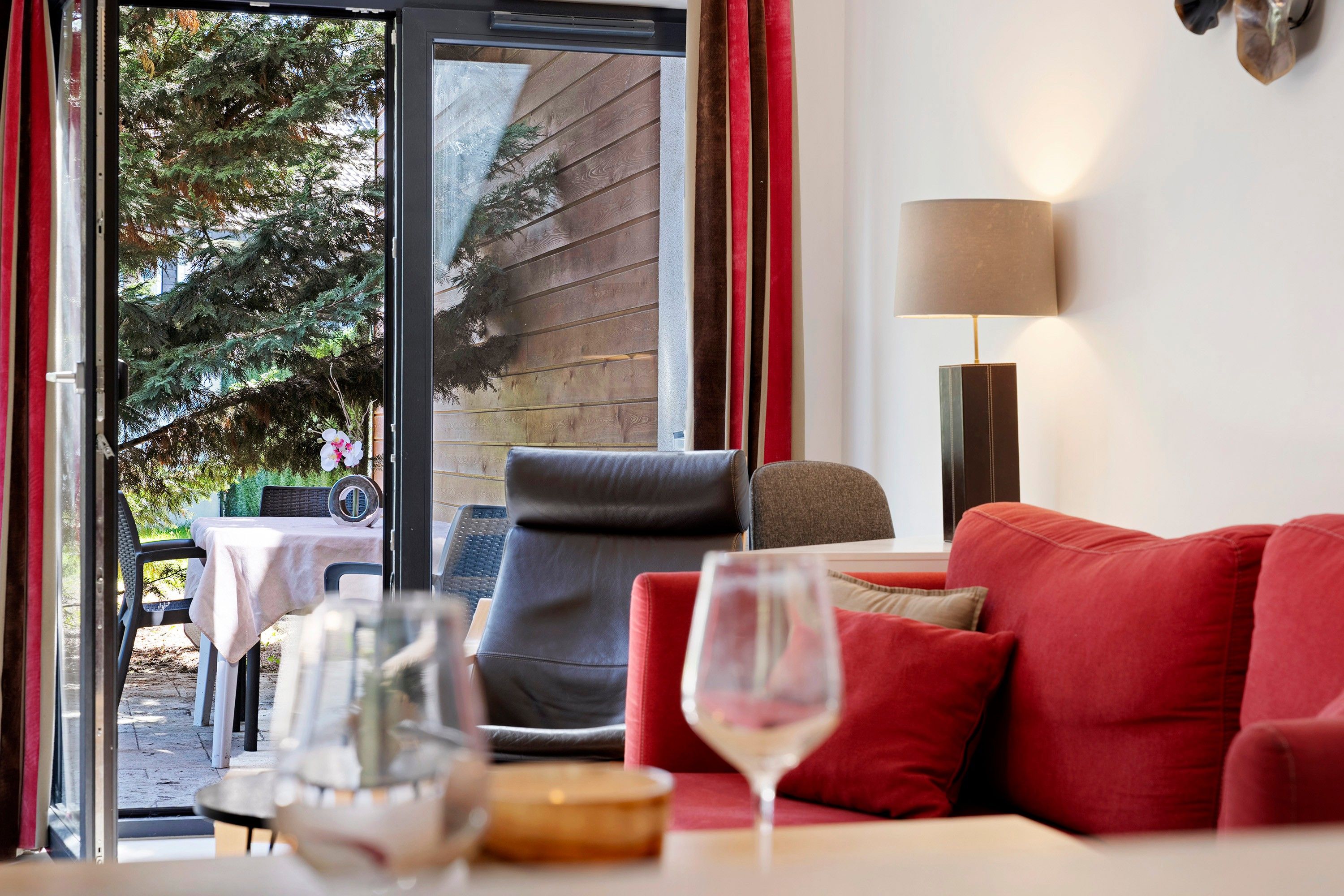 Una habitación con un sofá rojo, una mesa con un vaso y una lámpara.
