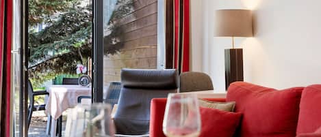 Una habitación con un sofá rojo, una mesa con un vaso y una lámpara.