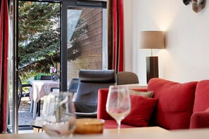 A room with a red sofa, a table with a glass, and a lamp.