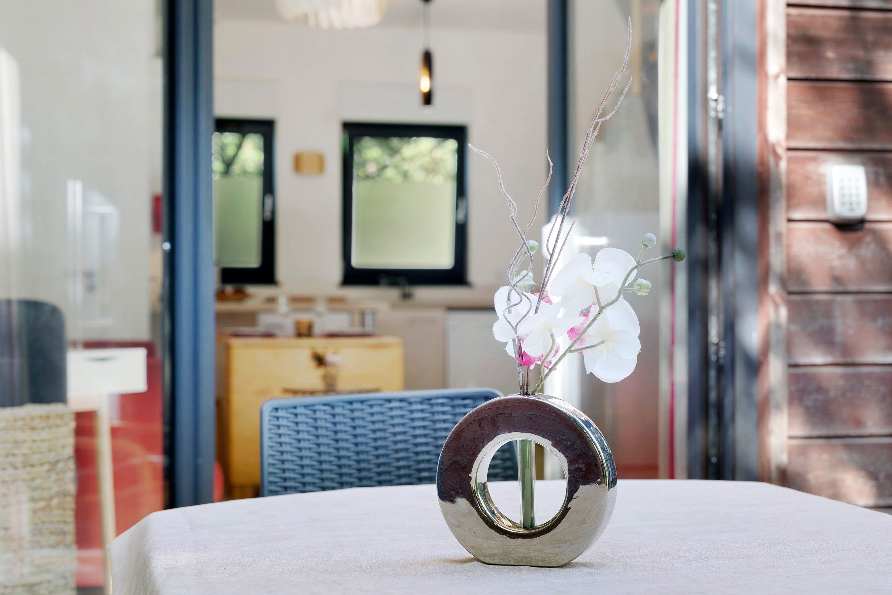 Een ronde spiegel met een reflecterend oppervlak op een tafel, met een vaas witte bloemen en groen in de voorgrond.