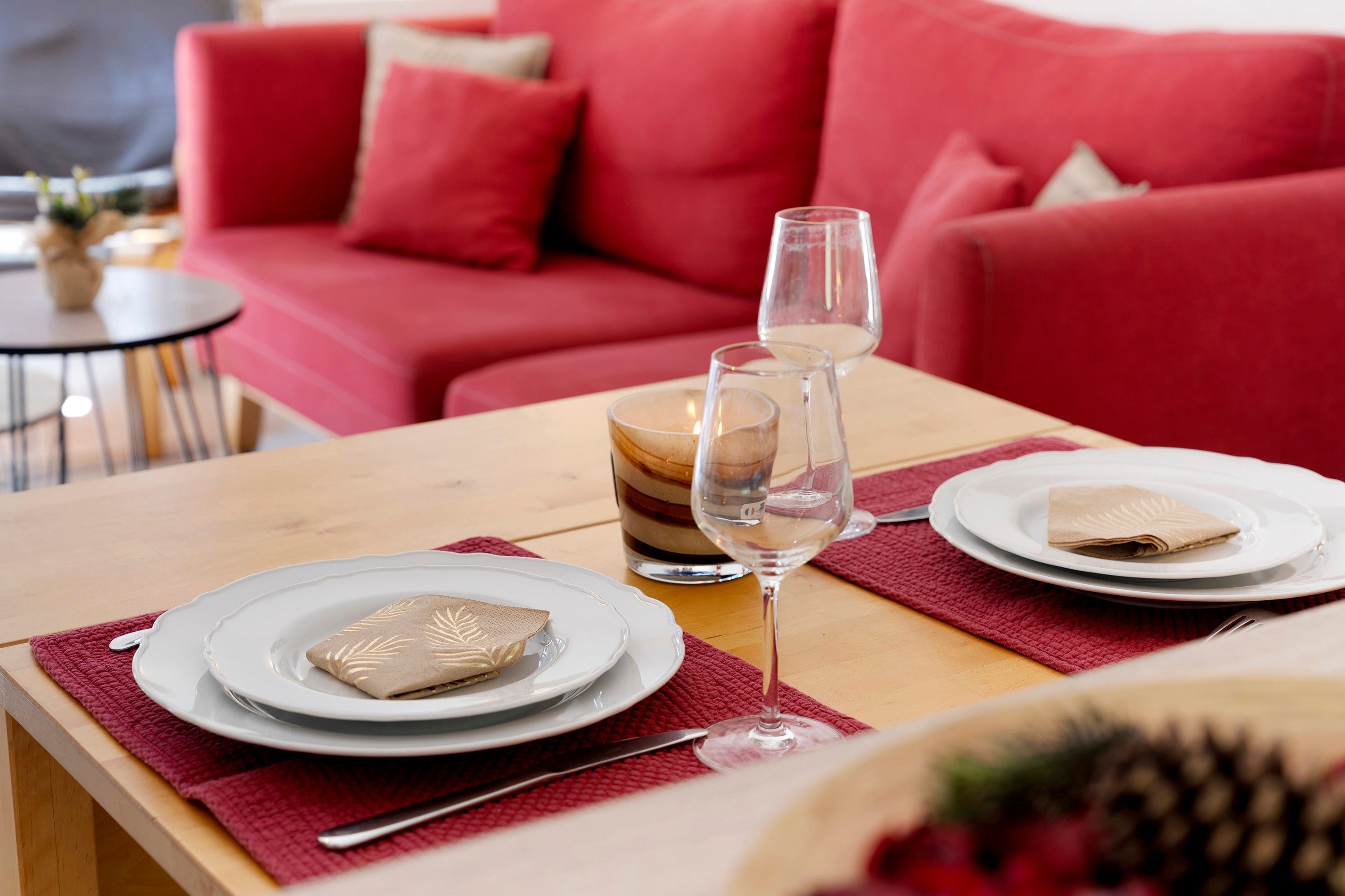 Une table à manger dressée avec des assiettes, un verre de vin et une bougie.