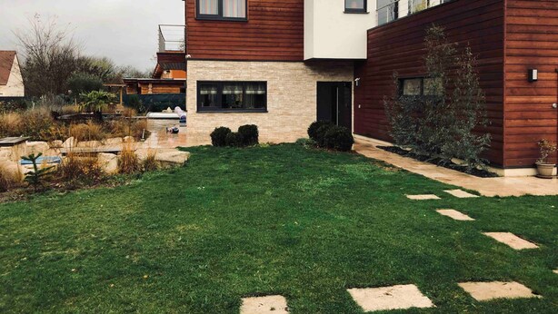 Una casa moderna de dos pisos con fachada de piedra y niveles superiores de madera.
