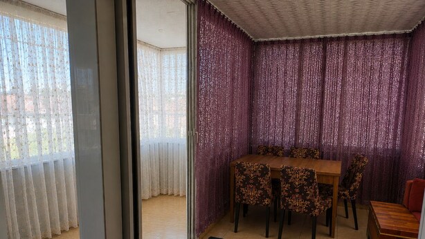 Un coin repas avec une table et des chaises, un tapis à motifs et une vue à travers une porte vitrée.