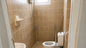 Une petite salle de bain comprenant des toilettes, un lavabo et un espace douche.