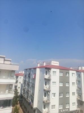 A multi-story residential building with balconies, a clear sky, and a bird in flight.