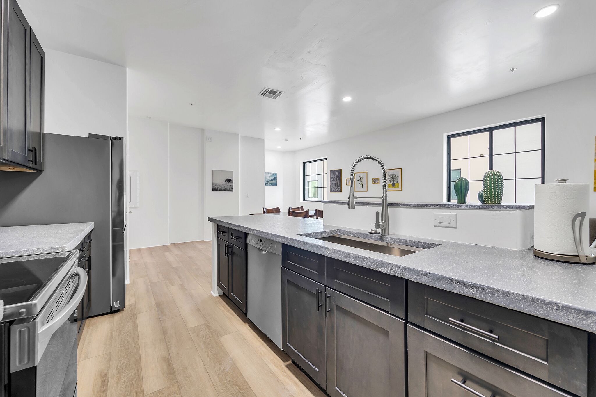 A modern kitchen with a central island, stainless steel appliances, and a large window.