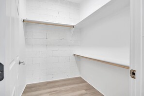 Ein Zimmer mit weißen Backsteinwänden, Holzdielen und zwei Holzregalen.