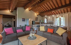 Ein modernes Wohnzimmer mit einem großen grauen Ecksofa, einem Holztisch und einer Küche im Hintergrund.