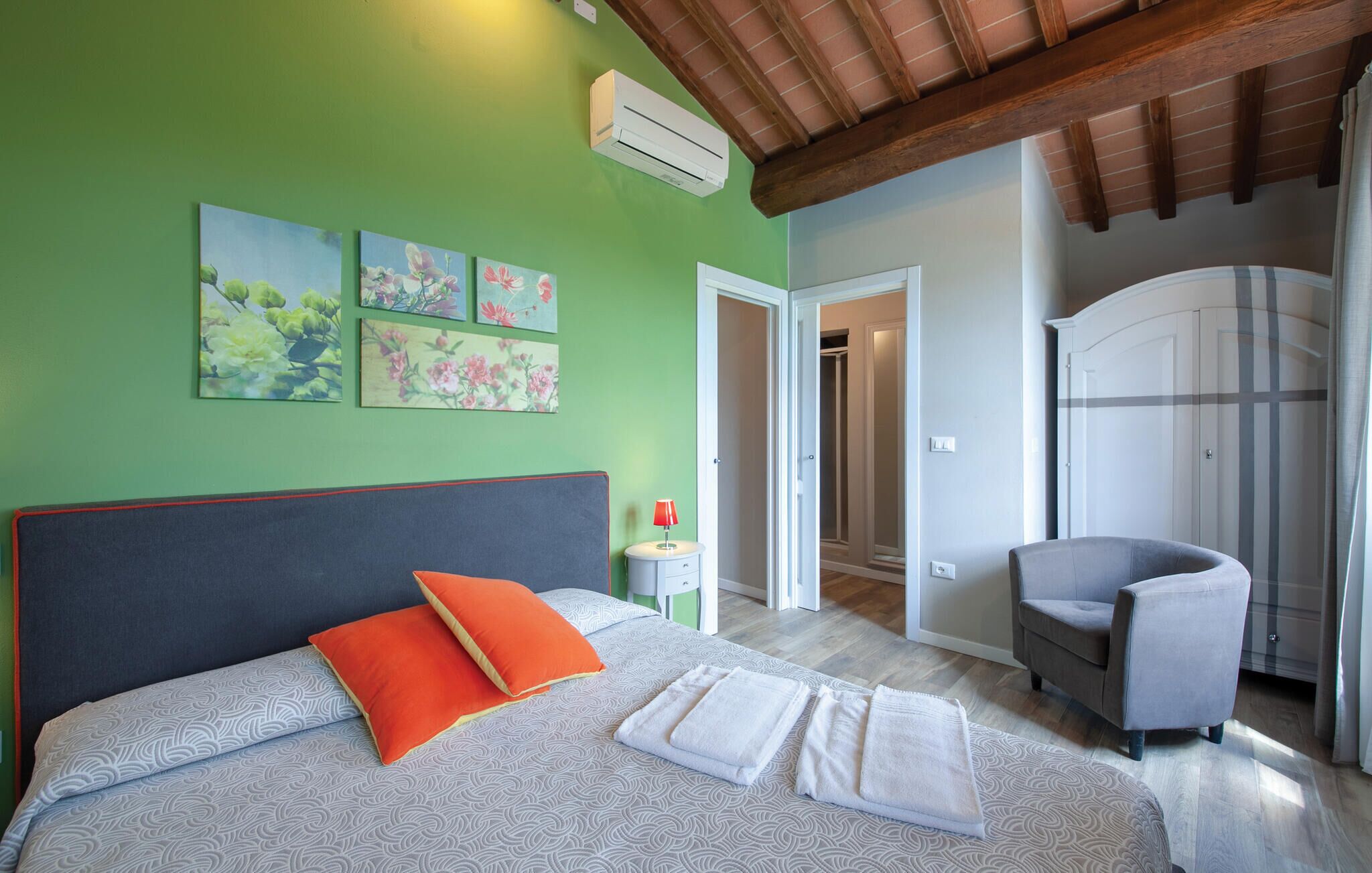 A bedroom with a bed, a chair, and a wardrobe.