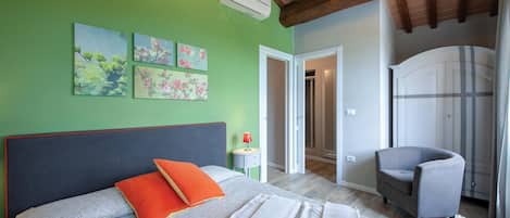 A bedroom with a bed, a chair, and a wardrobe.