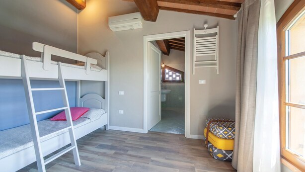 A room with bunk beds, a bathroom with a window, and a wooden floor. - Nice home in Lajatico with private swimming pool, can be inside or outside (Lajatico)