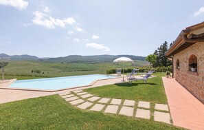Ein Schwimmbad mit Liegestühlen und Blick auf sanfte Hügel.