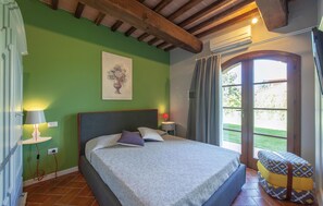 A bedroom with a bed, a bedside table, a lamp, a window with curtains, and a view of the outdoors. - Nice home in Lajatico with private swimming pool, can be inside or outside (Lajatico)