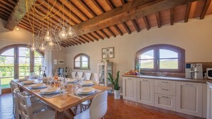A dining area with a wooden table set for six, surrounded by white chairs. - Nice home in Lajatico with private swimming pool, can be inside or outside (Lajatico)