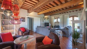 A spacious living area with a high wooden ceiling, a grey sofa set, a coffee table, and a bookshelf. - Nice home in Lajatico with private swimming pool, can be inside or outside (Lajatico)