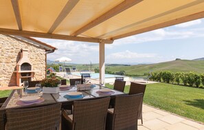 An outdoor dining area with a stone wall, a pool, and a view of rolling hills. - Nice home in Lajatico with private swimming pool, can be inside or outside (Lajatico)